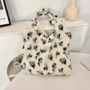 Close-up of floral sherpa tote bag with blue patterns on a minimalist white desk