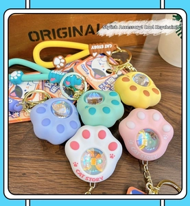 Macro detail of cat paw LED keychains in various macaron colors on a wooden surface