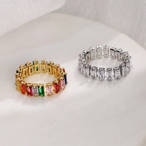 Close-up of gold and silver rings with rectangular zircon stones on white stone base