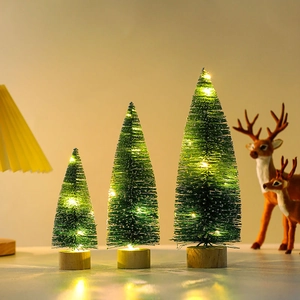 Close-up of three lighted mini Christmas trees with snow effect and wooden bases