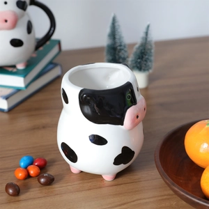 Close-up of 3D cow shaped ceramic coffee mug on a warm wooden desk with cozy home decor
