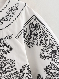 Détail de broderie florale noire de style bohème sur une veste en tissu blanc