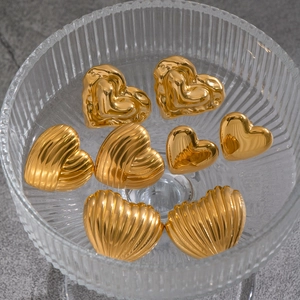 Detail of four textured gold heart-shaped metal studs in a ribbed glass bowl