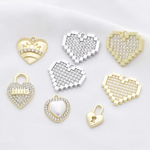 Assorted heart pendants with rhinestones and pearls on white fabric background