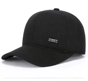 Detail view of black wool flat cap featuring a rectangular metal fashion logo plaque