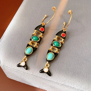 Macro detail of vintage fish earrings with black enamel and colorful gemstones
