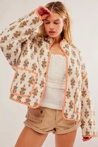Detail of off-white quilted floral jacket featuring orange piping and large patch pockets