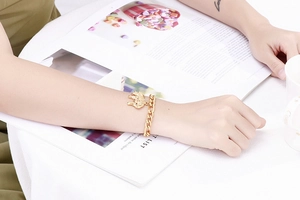 Close-up of a gold-plated elephant pendant bracelet on a woman's wrist with chain links
