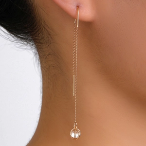 Detail of long gold chain tassel earring with round cubic zirconia pendant on model