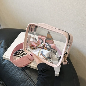 Detail of transparent PVC crossbody bag with pink trim and wide woven shoulder strap