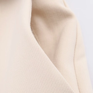 Detailed close-up of beige fabric texture and premium stitching on trousers