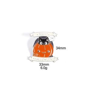 Macro shot of Halloween enamel pin with black cat inside orange pumpkin and banner