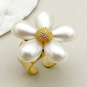 Detailed close-up of a large gold-plated flower ring with elegant white pearl petals