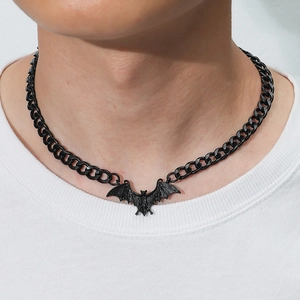 Close-up of gothic black bat pendant necklace worn by model with a steel cuban chain