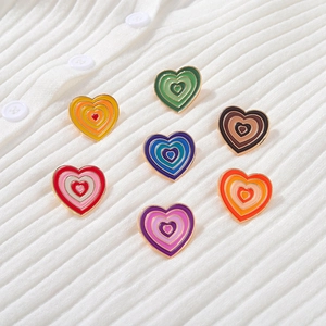 Detail of colorful enamel heart brooches in rainbow gradients on a white knit cardigan