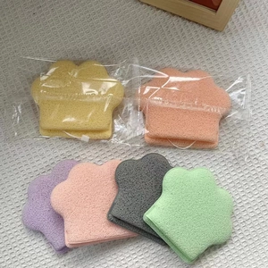 Cat paw shaped facial cleansing sponges in multiple colors on white waffle fabric