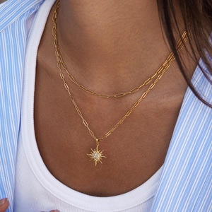 Collana a doppio strato in oro con pendente a sole e catena a graffetta indossata