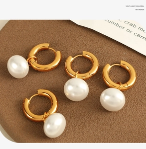 Macro shot of elegant gold hoop earrings with white round pearls on vintage paper