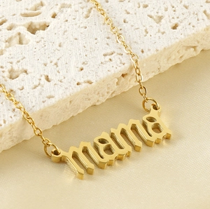 Gros plan d'un collier en acier doré avec pendentif Mama sur une surface en pierre