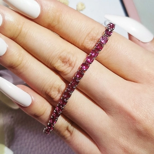 Detailed view of tennis bracelet featuring round-cut red zircons in a silver claw setting