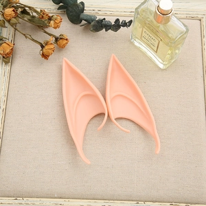 Detail view of skin-toned silicone elf ears for cosplay, placed on vintage props