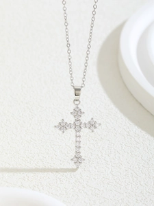 Close-up of sparkling cubic zirconia cross pendant on silver chain necklace