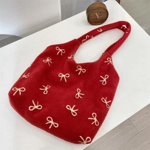 Détail du sac cabas rouge en peluche avec broderies de nœuds blancs et polaire douce