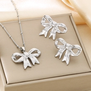 Silver hollow bow jewelry set with necklace and earrings on premium silk fabric
