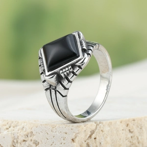 Macro view of men's vintage stainless steel ring with black stone on stone surface
