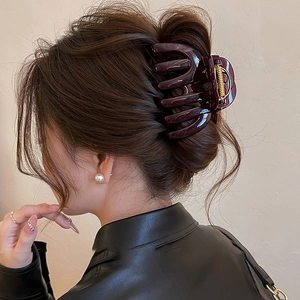 Macro detail of the dark red acrylic hair claw clip securing a full bun hairstyle
