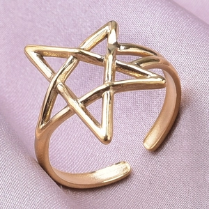 Close-up of golden stainless steel star ring on elegant purple silk fabric background