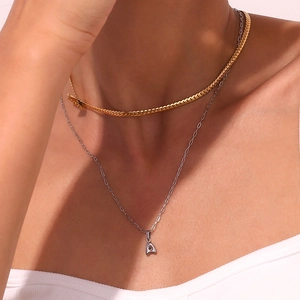 Detail of layered gold flat chain and silver A letter pendant necklace on model