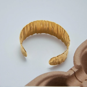 Detail of 18K gold stainless steel open bangle featuring unique vertical pleat textures