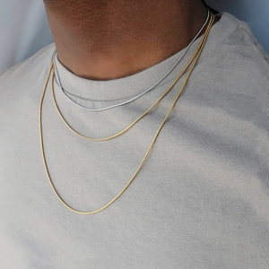 Detailansicht von drei mehrlagigen Schlangenketten aus Titanstahl in Gold und Silber