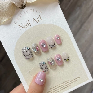 Detailed view of pink and silver glitter handmade press-on nails with 3D heart rhinestones