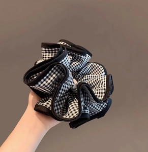 Gros plan sur le chouchou en tissu à carreaux noir et blanc avec texture douce à volants