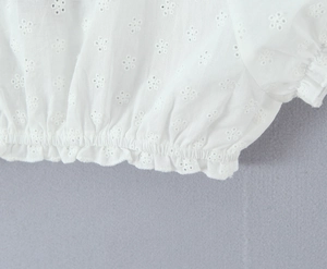 Dettaglio del tessuto in pizzo bianco con ricamo floreale e vita elastica