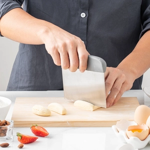 Baker cutting dough with a stainless steel scraper on a kitchen counter with flour