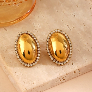 Elegant gold oval stud earrings with sparkling zircon inlay on marble background
