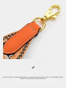 Close-up of orange lychee leather strap connectors with 5cm wide jacquard webbing and gold hooks