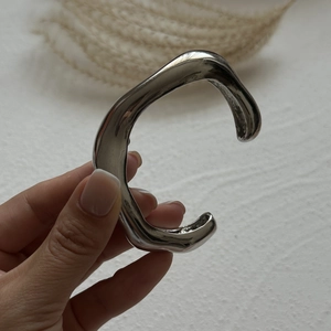 Detailed close-up of a silver multilayer C-shaped cuff bracelet with polished finish