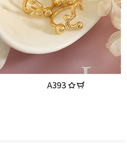 Close-up of golden heart beaded ring on a white ceramic tray with floral accents