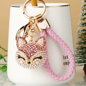 Close-up of pink rhinestone fox keychain with white pearls and woven leather cord