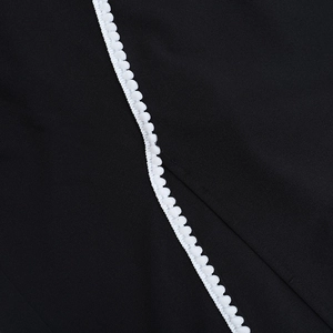 Détail de la robe noire avec garniture de pompons blancs et texture de tissu fine