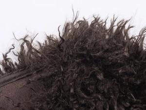 Macro view of fluffy dark brown faux fur texture with detailed curly fibers