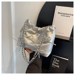 Close-up of metallic silver bucket bag with chain strap and elegant bow details