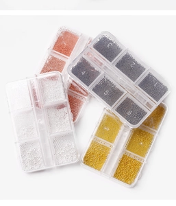 Detailed view of mini nail art steel beads in four metallic colors inside 6-slot storage boxes