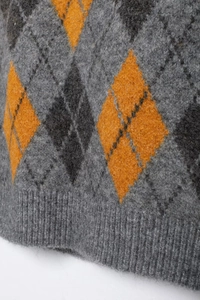 Close-up of the ribbed hem on a grey argyle knit vest with orange diamond patterns