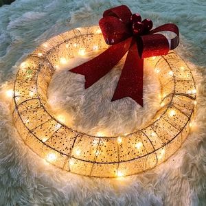 Christmas wreath with warm LED lights and a large red glitter bow on a plush rug