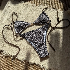 Detail view of leopard print bikini set featuring pearl buckle accents and smocking fabric
